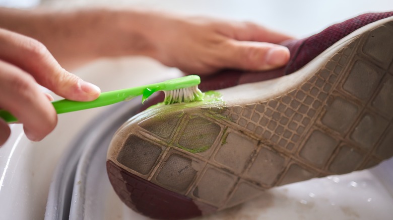 person cleaning shoe with toothbrush