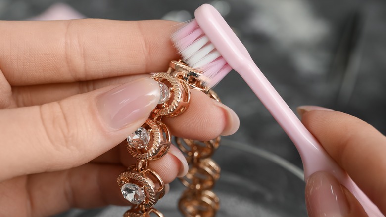 person cleaning jewelry with toothbrush