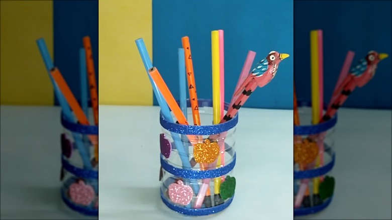 Small plastic vinegar bottle cut and decorated into a colorful pencil holder.