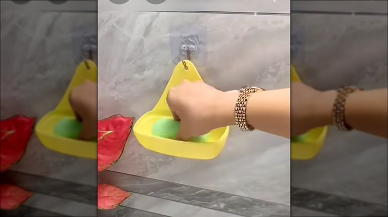 Woman grabbing a bar of soap out of a yellow soap caddy in the shower.