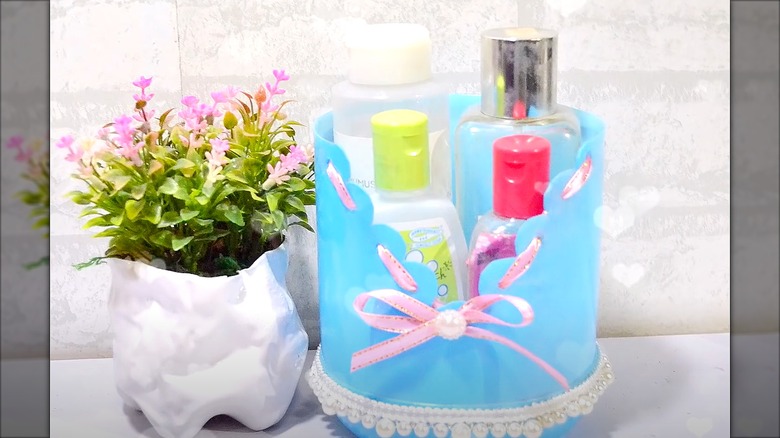 Blue toiletry basket with four bottles in it next to a planter.