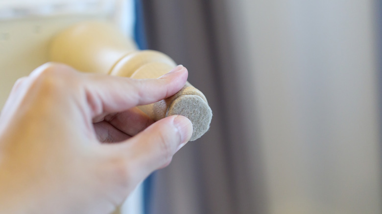 A person presses a felt disc to the bottom of a furniture leg.