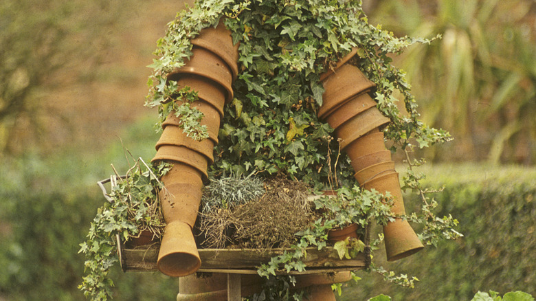 A statue of a gardener made from old orange plastic plant pots