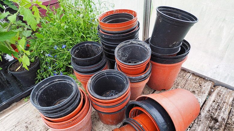 A pile of used black and orange plastic nursery pots on a garden potting table