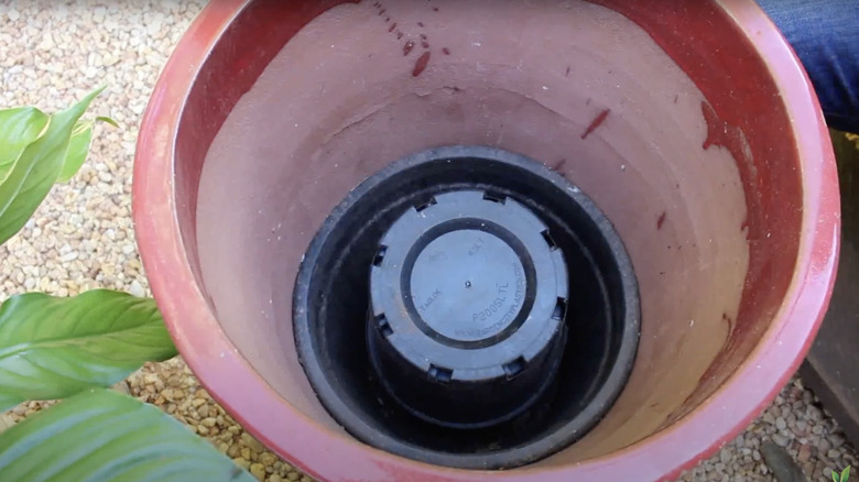 A plastic planter placed in the bottom of a large pot saves on soil