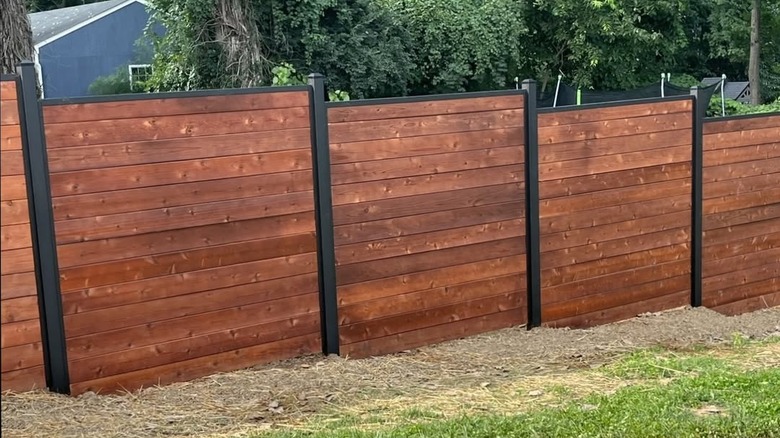 red wood fence with black frame installed on hill