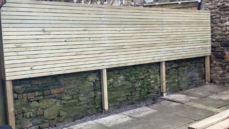 Wood upper half-fence in front of stone wall