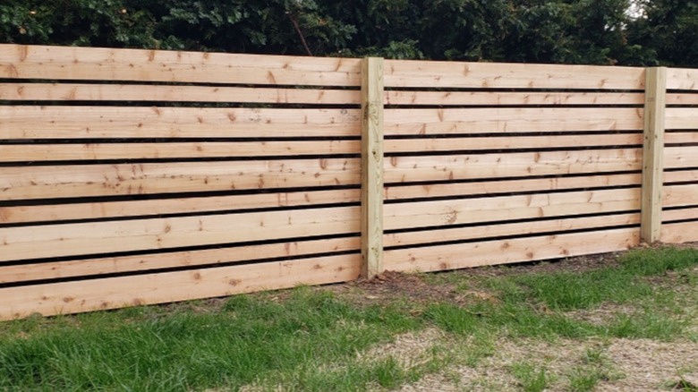 Wood fence with varying sized wood planks in yard