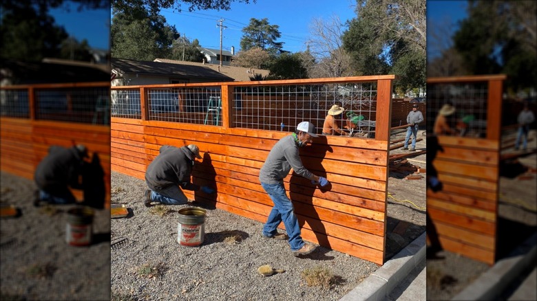 Men building wood fence with wire mesh