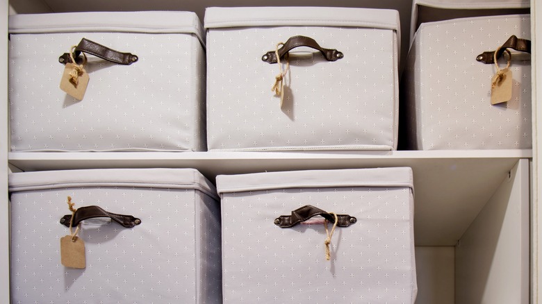 Pretty boxes with labels hanging from the handles in a closet