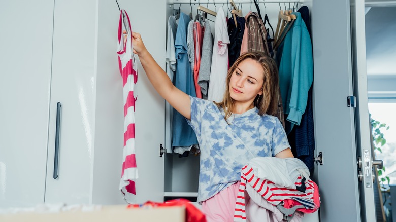 Woman holding a top while organizing her closet