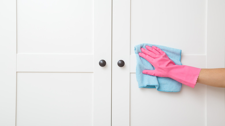 Gloved hands wiping white closet doors