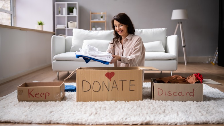 Woman decluttering her closet and putting clothes in different boxes