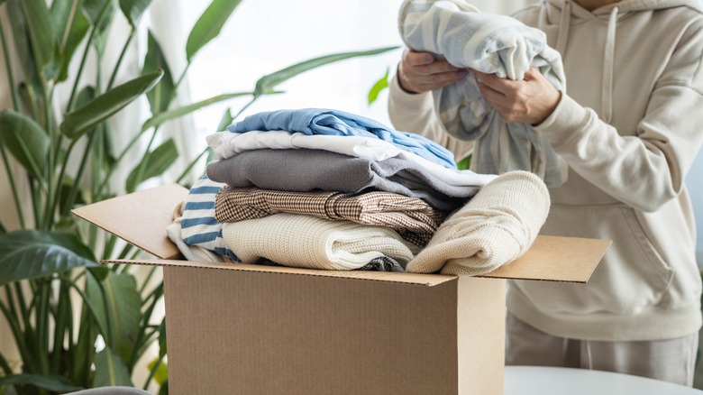 Person putting clothes in a cardboard box