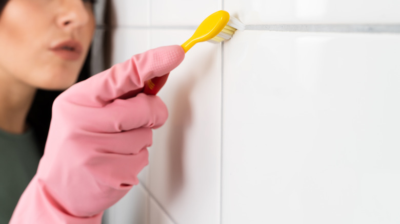 Woman using toothbrush on grout