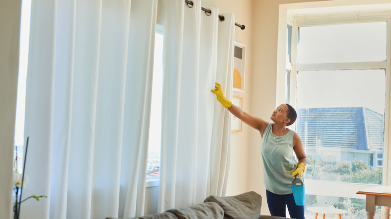 Woman cleaning drapes