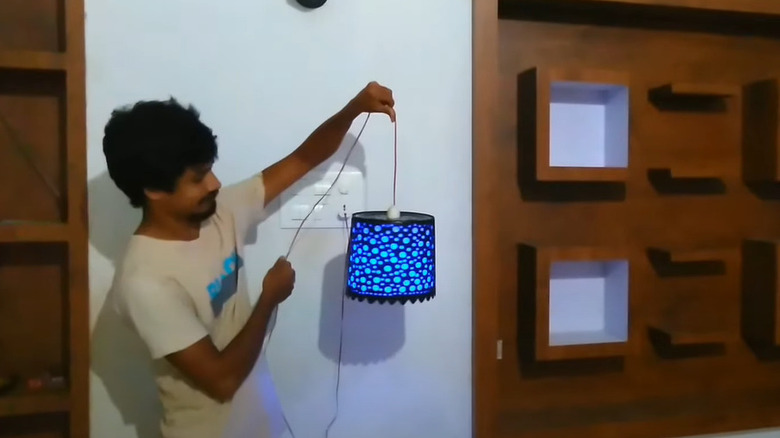 man holding glowing bucket pendant