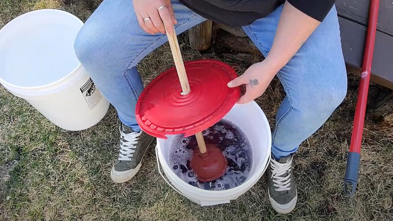 woman using bucket plunger washer