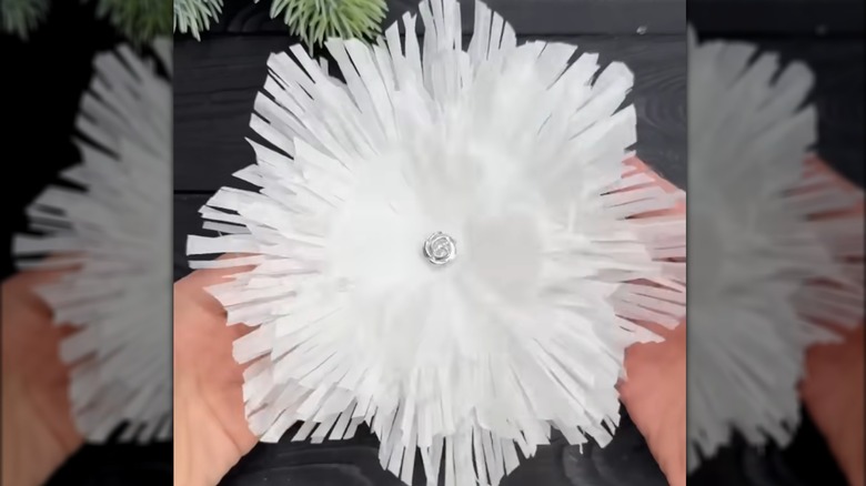 Hands holding white snowflake made from cupcake liners