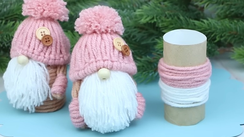 Pink and white yarn gnomes wrapped around toilet paper sleeves