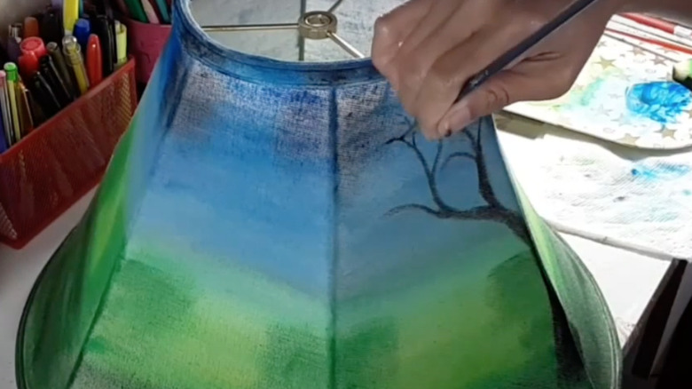 person hand painting lampshade