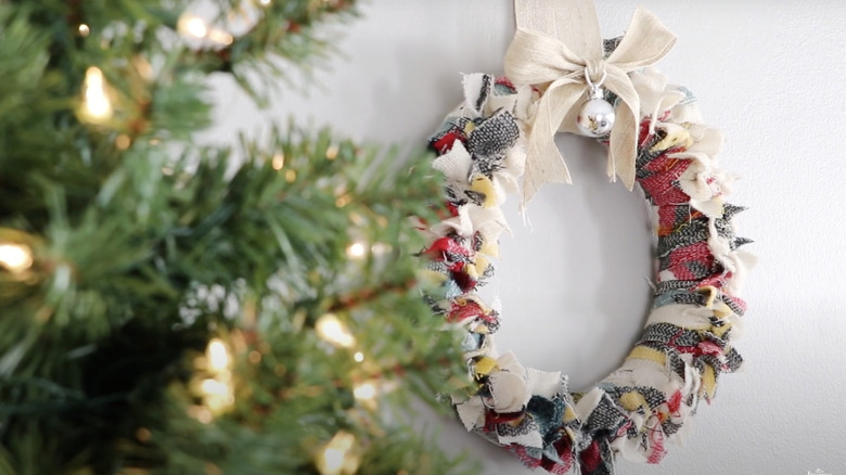 A wreath hangs behind a Christmas tree.