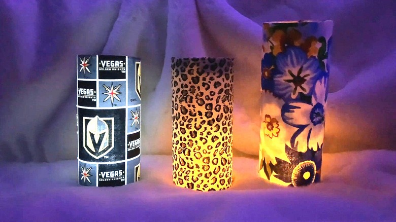 Three fabric-covered glass candle holders with lit candle inside