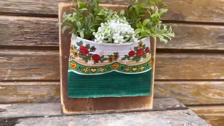 A vase made from a fabric-wrapped tin can with foliage