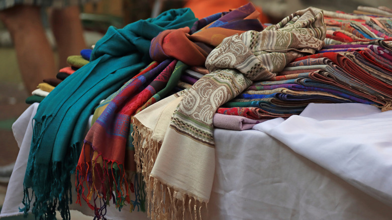 A variety of different scarves are neatly folded on table.