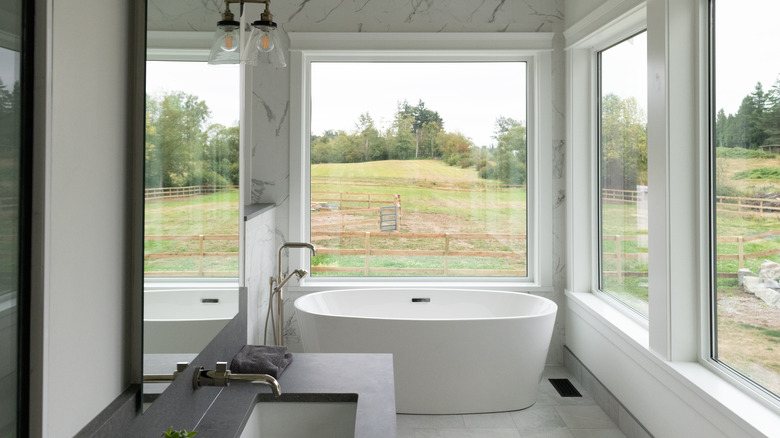 large windows above white bathtub