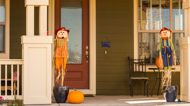 Two smiling scarecrows on porch