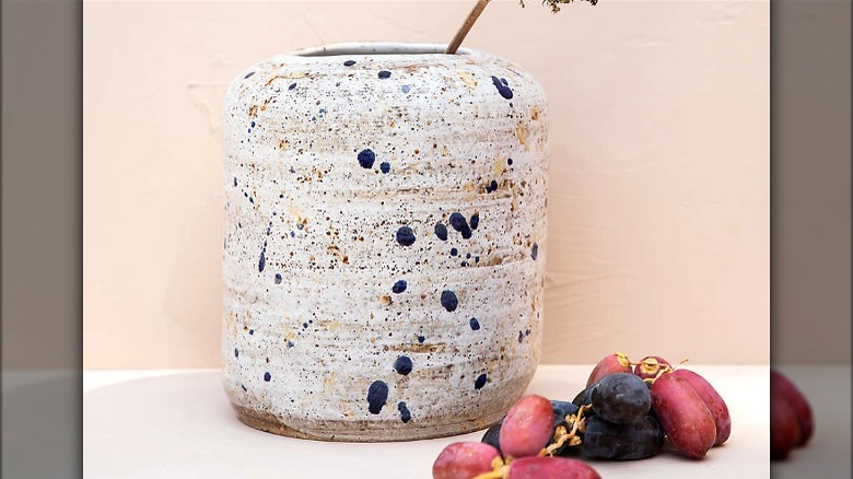 Speckled ceramic vase and grapes