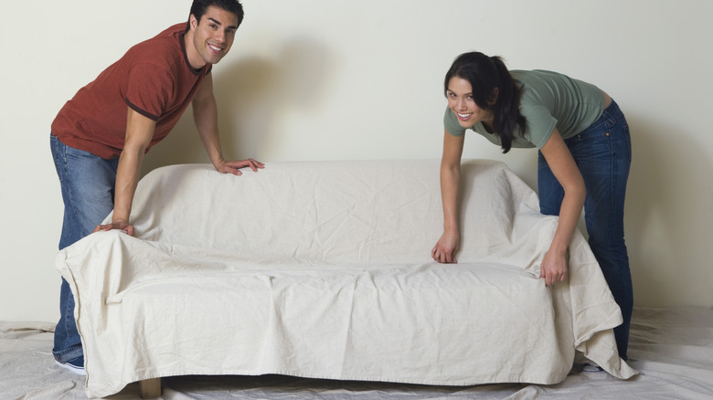 couple putting slipcover on furniture