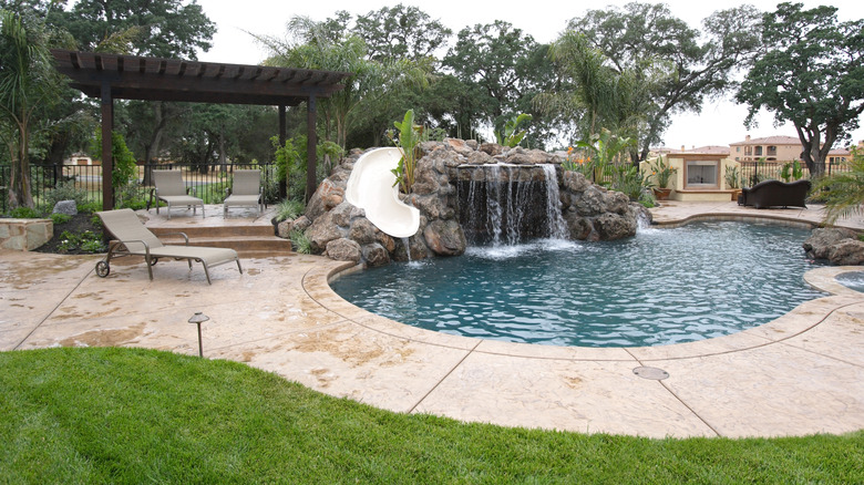 luxury backyard with tropical landscaping and waterfall in pool