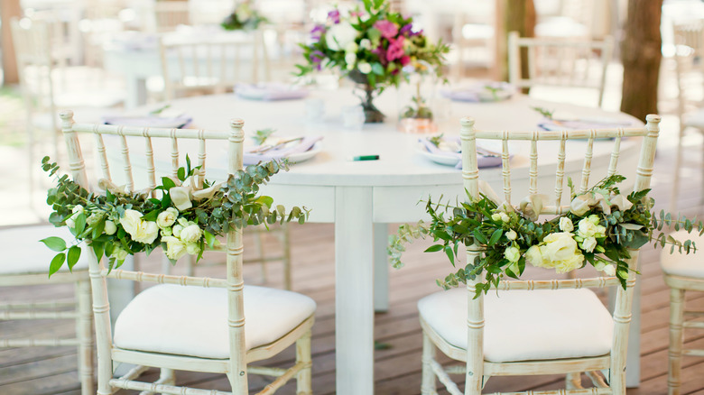 flower garlands on white chairs