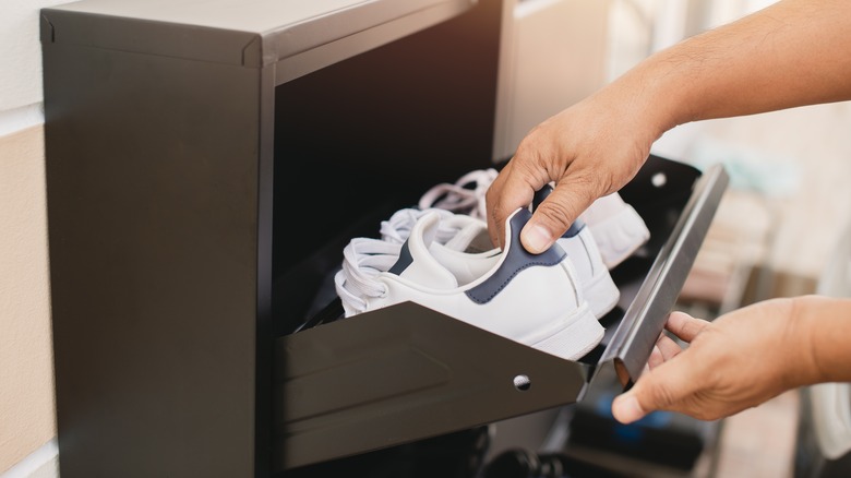 person placing sneakers inside cabinet