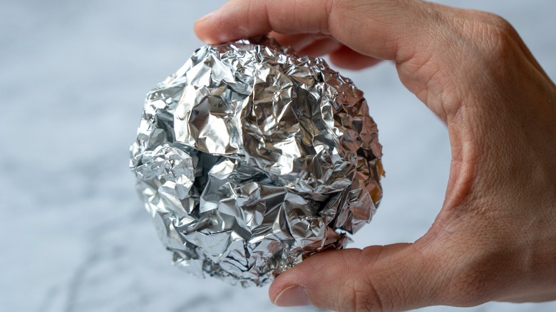 hand holding aluminum foil ball