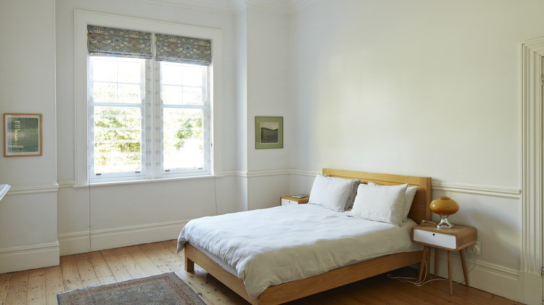 A white bedroom with wood flooring