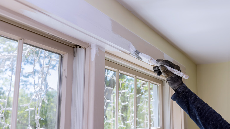 Person painting window trim