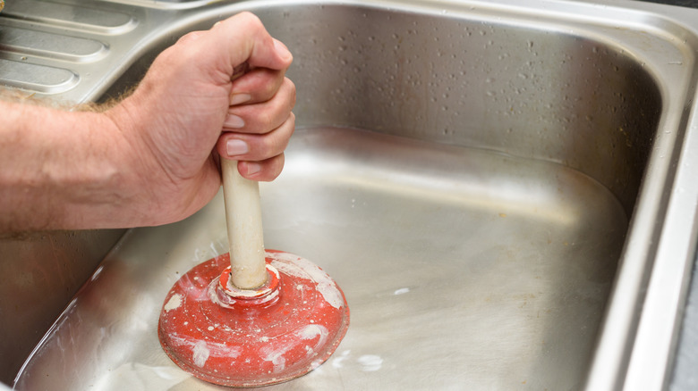 Person using plunger on sink