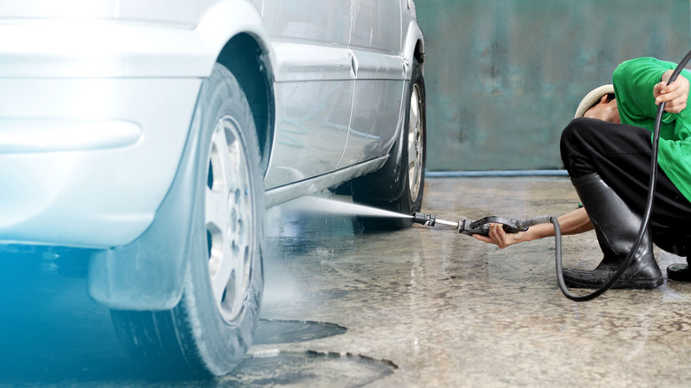 crouching worker sprays under car