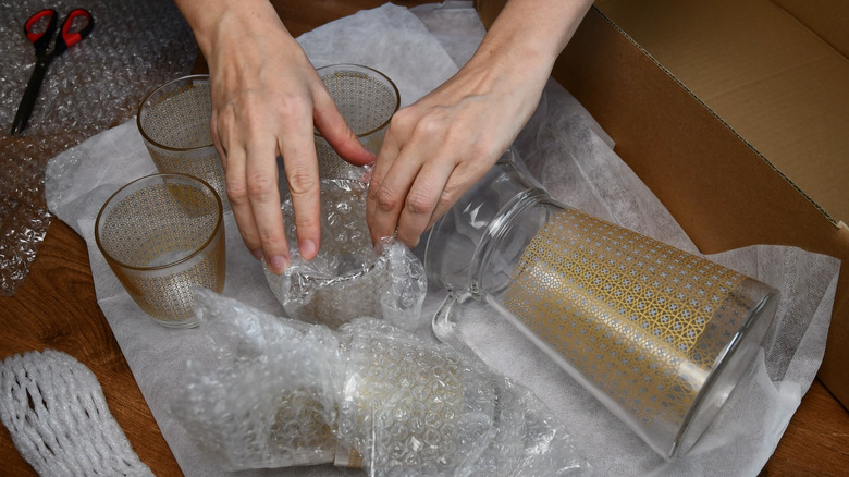 person wrapping glassware