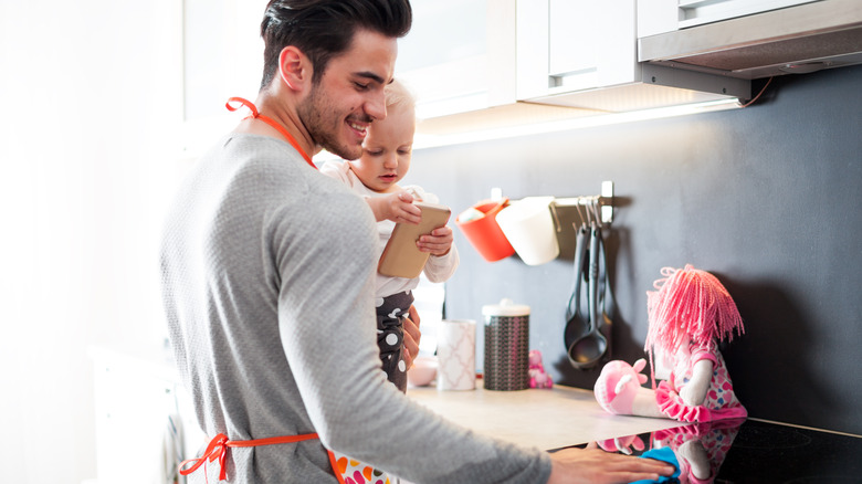 dad holding baby while cleaning