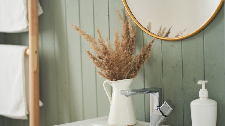 Gold mirror in bathroom with green walls