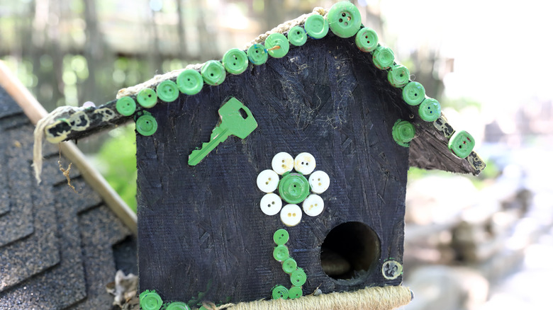 A birdhouse decorated with buttons