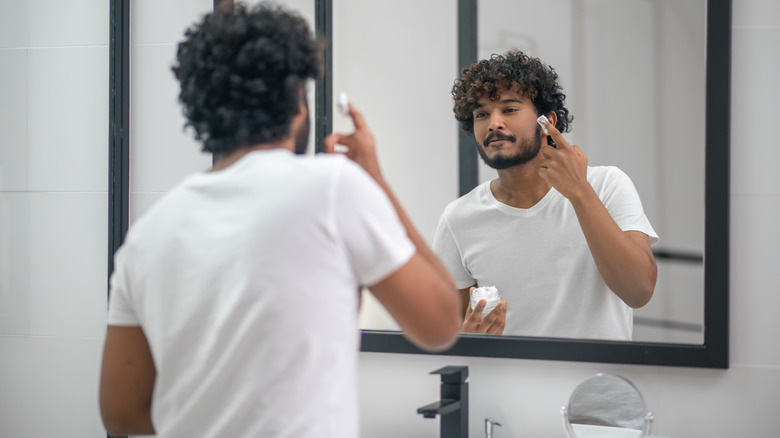 Grinning man applying shaving cream