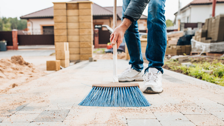 Person sweeping dirt from walkway