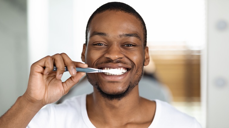Man brushing teeth while smiling