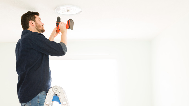 man installing light fixture 