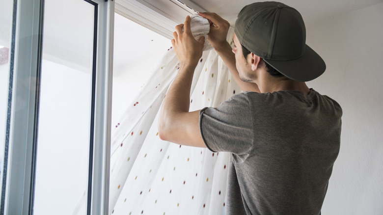 man installing curtains